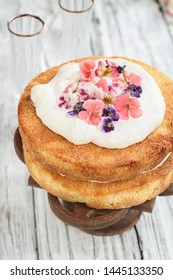 Victoria Sponge Cake With Whipped Cream And Sugared Flowers Over A White Wooden Rustic Table Top. Image Shot For Above.