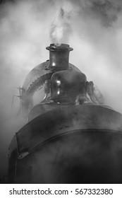 Victorian era steam train engine with full steam in black and white