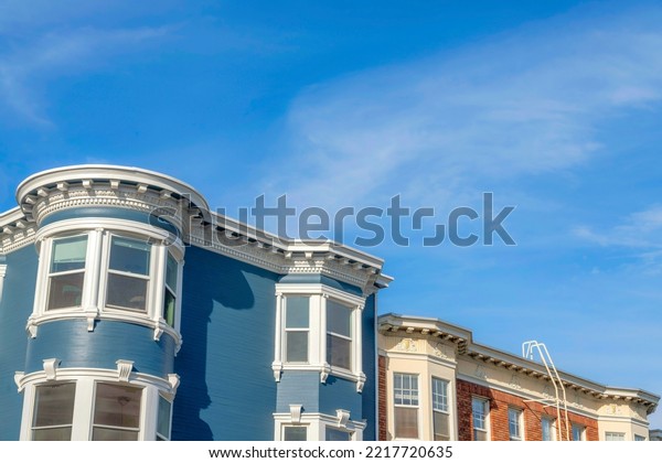Victorian and georgian style residential\
buildings in San Francisco, California. There is a blue victorian\
style on the left near the georgian building on the right with\
bricks and emergency\
stairs.