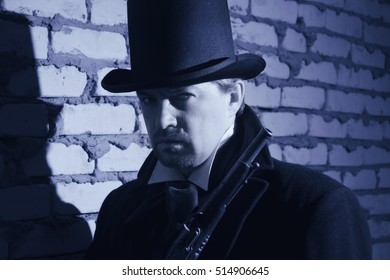 Victorian man in the black coat, top hat and in a tie on a wall background