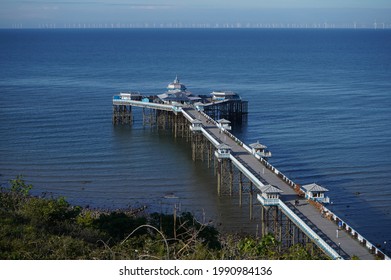 The Victorian Pleasure Pier At Llandudno, North Wales, UK, From Above: An Offshore Wind Farm In The Background.                             