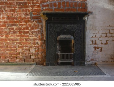 Victorian style open fireplace with red brick wall surround. 