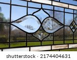 Victorian style stained glass panel with beveled glass element in center against a blue sky.