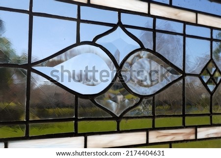 Victorian style stained glass panel with beveled glass element in center against a blue sky.