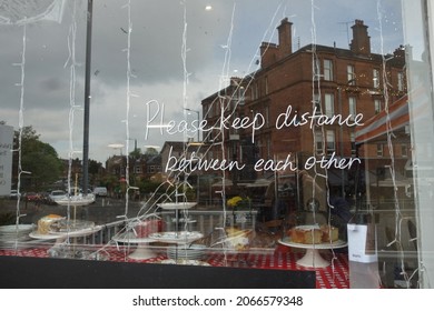 Victorian Tenement Reflections In A Glasgow Cafe Window With A Hand-written Sign Reminding Patrons To Keep Their Distance During Covid Lockdown.