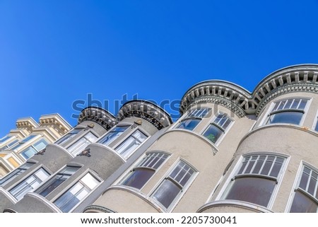 Victorian townhouses with curved window walls at San Francisco, California. Low angle view of townhomes with corbel roofs and dentils against the clear sky.