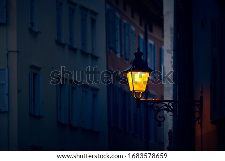Victorian vintage street lantern with yellow warm light at the evening on the italian mysterious street by night