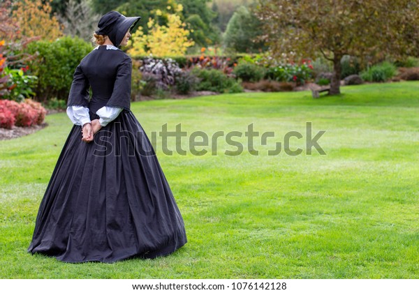 Victorian woman in black\
dress and bonnet