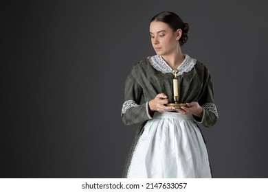 A Victorian Woman Wearing A Dark Green Checked Bodice And Skirt And Holding A Candle