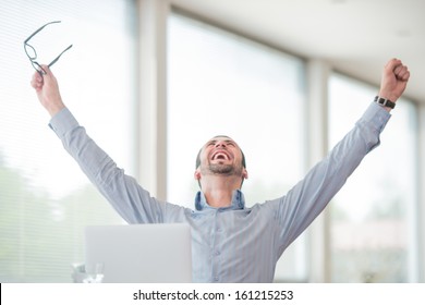 Victorious corporate man celebrating with his arms lifted in the air - Powered by Shutterstock