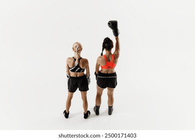 Victorious female boxer raising hand in glove in triumph isolated on white background. After intensive match. Concept of combat sport, martial arts, strength, endurance. Back view - Powered by Shutterstock