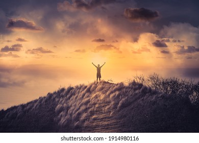 Victorious man on a mountain with arms up to the sky. 