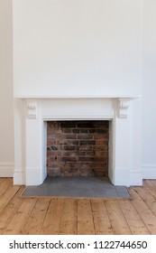 Victoriran wooden fireplace surround with white walls and wooden floor