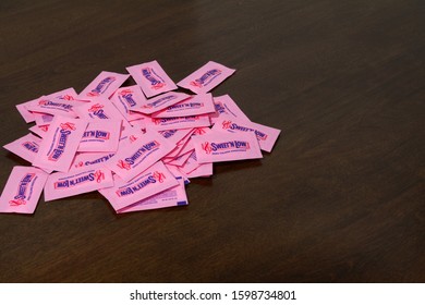 Victorville, CA / USA – December 18, 2019: A Pile Of Pink Artificial Sweetener Packets Of Sweet ’N Low Spread On A Brown Table.