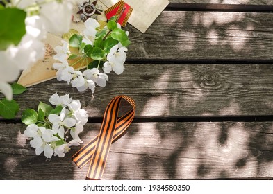 Victory Day card - St. George ribbon and apple-tree flowers on an old wooden background with copy space - Shutterstock ID 1934580350