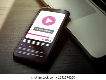 Video Advertising Youtube Business Concept. Smartphone Lying On A Dark Wooden Table With Ads Media On The Screen. Digital Marketing With Online Broadcasting And Streaming Video Advertising Content