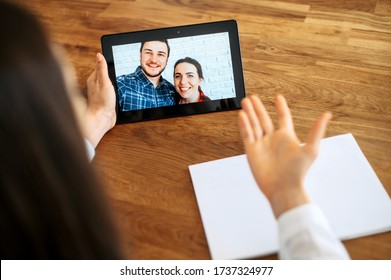 Video Appointment Online With Family Psychologist, Doctor. Back View A Woman In Formal White Shirt Is Communicating Via Video With A Couple On The Tablet Screen. Video Meeting