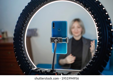 Video blogging. Business style woman talking to camera and recording video with smartphone and ring light lamp at home, working from home concept, social distant reality - Powered by Shutterstock