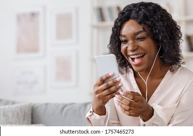 Video Call. Cheerful Black Woman Talking With Friends Online Via Smartphone At Home, Sitting On Comfortable Couch In Living Room, Copy Space