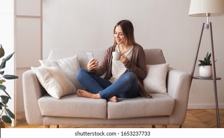 Video call. Cheerful young woman with coffee talking with friends on cell phone, panorama - Powered by Shutterstock