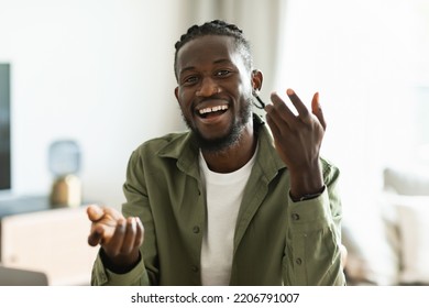 Video Call Concept. Happy African American Man Talking To Camera, Gesturing And Smiling, Sitting At Workplace At Home. Modern Remote Communication And E-teaching