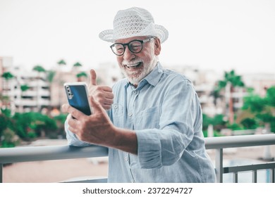 Video call concept. Happy smiling bearded senior man thumb up talking on mobile phone using phone webcam to communicate in video chat - Powered by Shutterstock