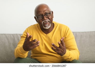 Video Call Concept. Senior African American Man Talking To Camera Sitting On Couch Indoors. Modern Remote Communication, Online Consultation And E-Teaching. Front View