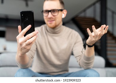Video call, distance is not a hindrance, young good-looking, sincere man is using a phone for video connection, on a meeting with a girl, business partner, colleague, sitting at home, pleasant sms - Shutterstock ID 1923909323