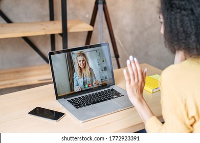 Video Call To Female Employee Or Friends. Two Woman Is Talking Online Via Video Connection On Laptop Indoor, They Are Greeting Each Other. Virtual Meeting