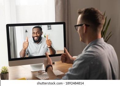 Video Call, Video Meeting. A Young Man Is Discussing Some Business Tasks With A Young African Man Via Video, They Have Come To A Consensus And Show Thumbs Up As A Sign Of Successful Negotiations