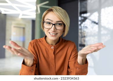 Video call online meeting, blonde businesswoman talking to colleagues remotely looking at camera smiling and gesturing, partner meeting online, webcam view, female employee working inside office. - Powered by Shutterstock