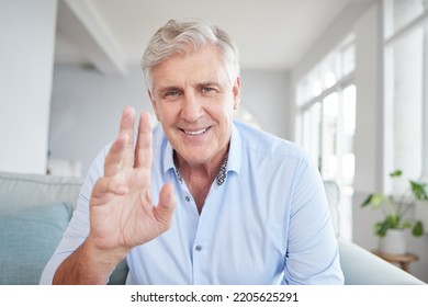 Video Call Portrait, Senior Greeting And Man In Communication On A Webinar, Virtual Conference Or Meeting On The Internet On Living Room Sofa In Home. Mature Business Person Waving On Web Seminar