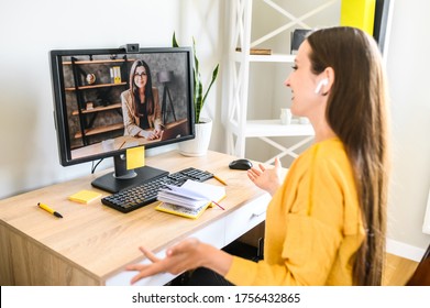 Video call, virtual meeting. Two young female co-workers is talking online via video connection
