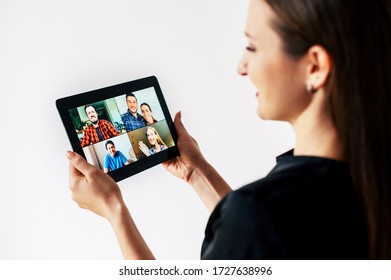 Video Call. A Woman Is Using Digital Tablet For Conversation With Several People At Same Time Together. Back View. Isolated On White Background