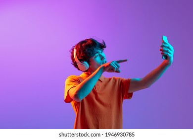 Video call  Young man talking phone isolated over pink  purple background in neon light  Future  gadgets  digital technology concept  Human emotion  facial expressions  Copy space for ad  design 