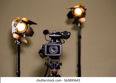 Video Camera (camcorder) On A Tripod And Two Halogen Spotlights With Fresnel Lenses. Shooting An Interview.