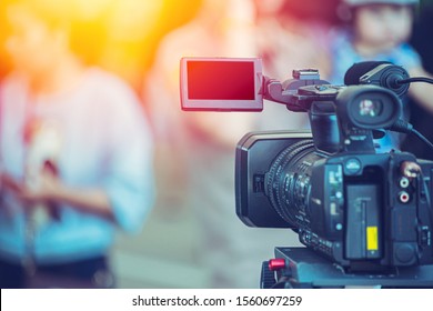 Video camera camcorder operator working at live event broadcasting blue color tone.