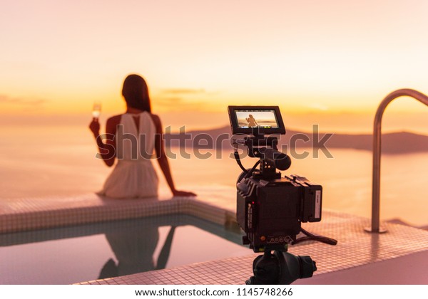 Video camera\
filming actress woman acting for movie on luxury hotel location\
behind the scenes of shoot. Professional videography equipment\
shooting outdoor at\
sunset.