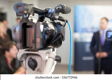 Video Camera In Focus, Blurred Spokesman In Background