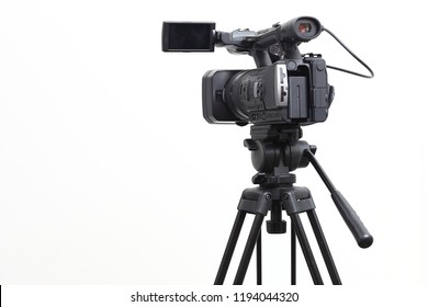 The video camera with the microphone is standing on the tripod isolated on white, in concept of technology, modern, entertainment.