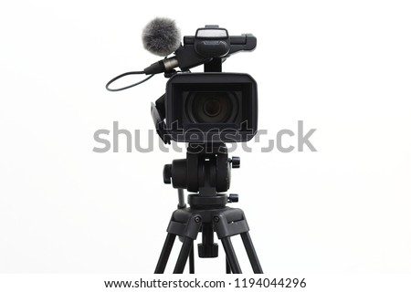 The video camera with the microphone is standing on the tripod isolated on white, in concept of technology, modern, entertainment.