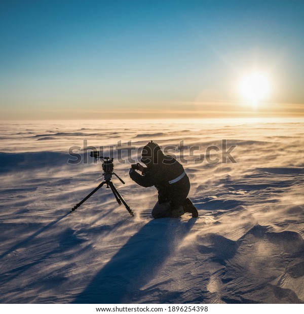 Video camera on tripod in the Antarctic desert at\
time sunset.