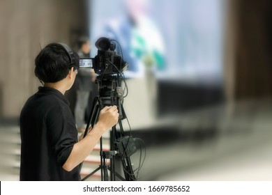 Video Camera Operator Professional Cameraman On Stage To Record Event With Camera Equipment For Entertainment,Focus On Camera And Blur Background