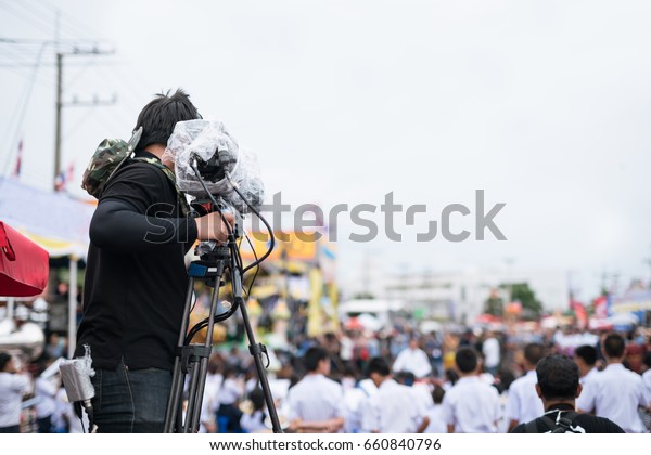 Video camera operator working with his\
professional equipment in hand at parade\
festival.
