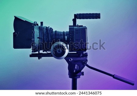 Video camera rig on a tripod, ready for shooting. Professional type of equipment, symbol of filmaking industry and entertainment. Side view, color graded shot