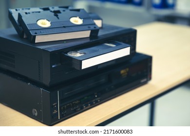 Video Cassette Tapes VHS In The Video Tape Player And Pile Stack Concept Of Old Retro Style Or Vintage Electric And Electronic Appliances Multimedia Record Playback Device Old Fashioned.