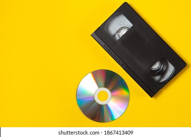 Video cassette videotape and compact disc on a yellow background. Flat lay concept.