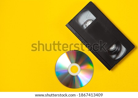 Video cassette videotape and compact disc on a yellow background. Flat lay concept.