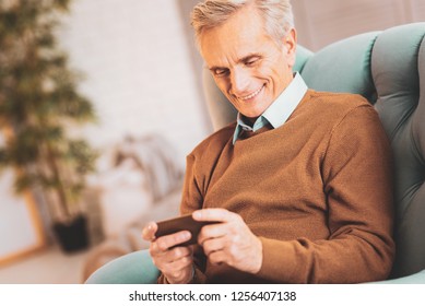 Video Chat. Aged Satisfied Man Feeling Impressed While Enjoying Communicating Via Video Chat With His Family Members