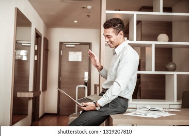 Video Chat. Dark-haired Beaming Man Having Video Chat With His Family While Having Business Trip